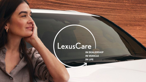 Woman looking into the distance beside a parked Lexus vehicle.