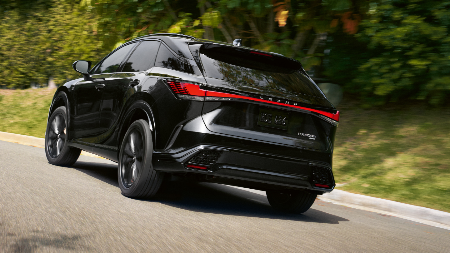 An RX F SPORT Performance drives along a street surrounded by greenery.